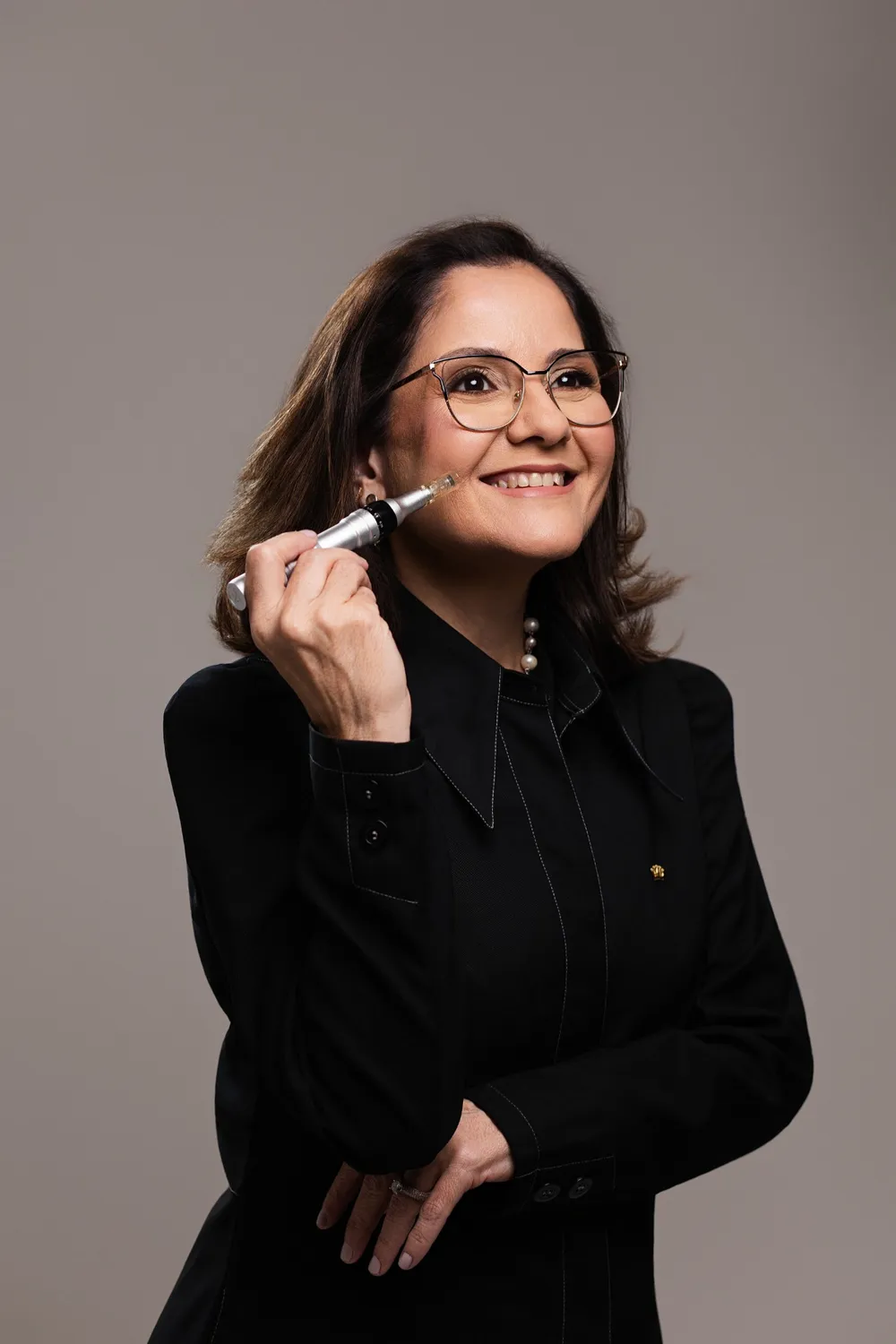Adriana Muniz sorrindo, com um equipamento de cuidado da pele próximo ao rosto